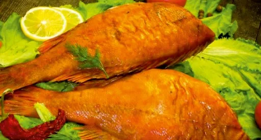 Рыба горячего копчения с золотистой корочкой на листьях салата